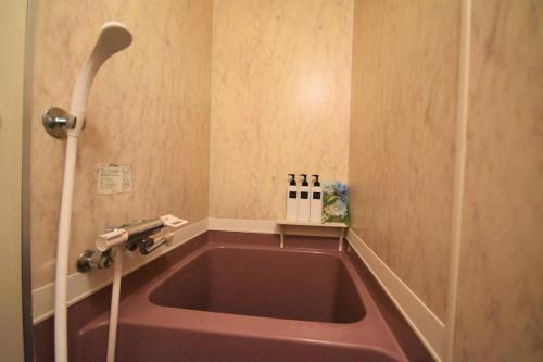 Tresor Misono - Vacation STAY 7905 في سابورو: حوض استحمام وردي في الحمام مع دش