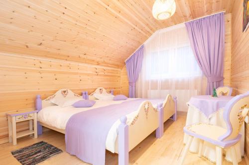 two beds in a wooden room with purple curtains at Cabana cu Flori in Porumbacu de Sus