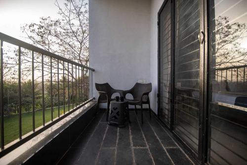 a balcony with a table and two chairs on it at Earth Song by StayVista - Boasting an Open theatre, Games, Spacious lawn, Swimming pool & Conference room in Pune