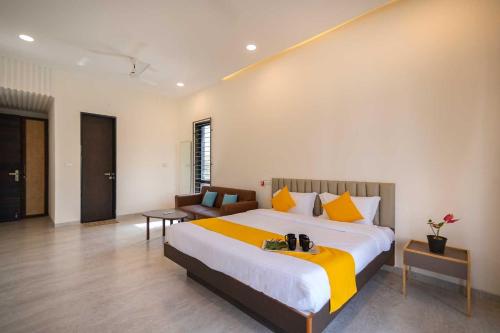a bedroom with a large bed and a couch at Earth Song by StayVista - Boasting an Open theatre, Games, Spacious lawn, Swimming pool & Conference room in Pune