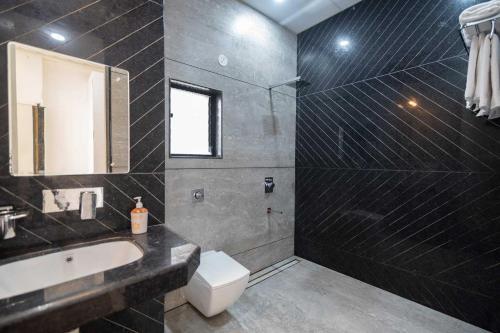 a bathroom with a sink and a toilet and a mirror at Earth Song by StayVista - Boasting an Open theatre, Games, Spacious lawn, Swimming pool & Conference room in Pune