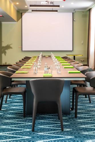 a conference room with a long table with chairs and a white screen at Wyndham Garden Burabay in Borovoye