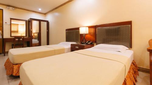 a hotel room with two beds and a desk at Peace Hotel by RedDoorz in Manila