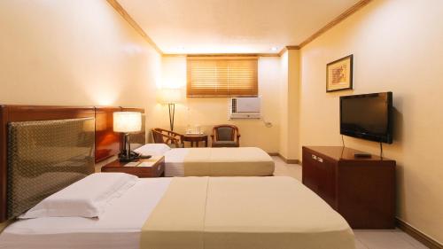 a hotel room with two beds and a flat screen tv at Peace Hotel by RedDoorz in Manila