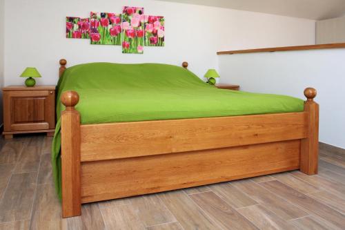 a bedroom with a bed with green sheets and flowers on the wall at Apartment LuVi in Korčula