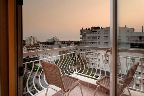 a balcony with two chairs and a view of a city at Lara Dinc Hotel in Antalya