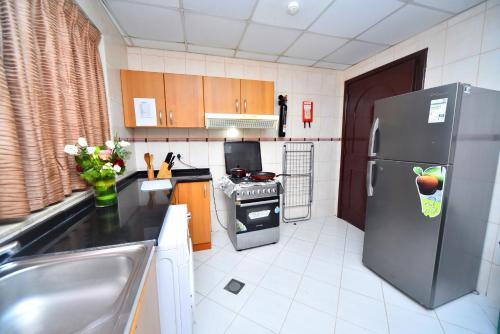 a kitchen with a stainless steel refrigerator and a sink at Emirates Stars Hotel Apartments Sharjah in Sharjah