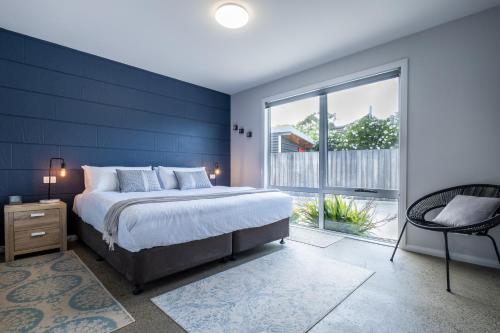 a bedroom with a large bed and a large window at Amaroo 1 - Freycinet Holiday Houses in Coles Bay