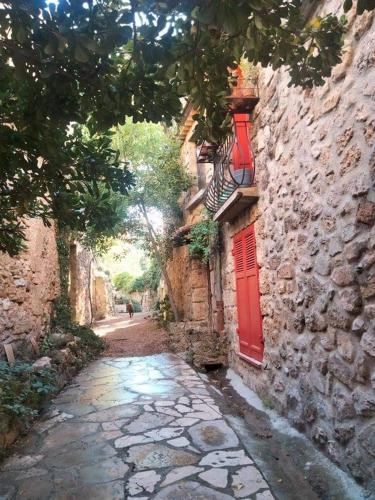 an alley with a red door on a stone building at 4 safraniers in Sillans-la Cascade