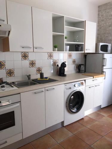 una cucina con armadietti bianchi e lavatrice di BERNARDINI Emplacement exceptionnel a Sari Solenzara