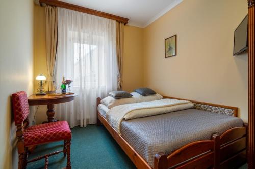 um quarto com 2 camas, uma mesa e uma janela em Hotel Garni Na Havlíčku em Kutná Hora
