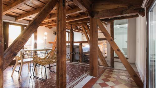 um quarto com vigas de madeira, uma mesa e cadeiras em La Casa de la Tuerta by Toledo AP em Toledo