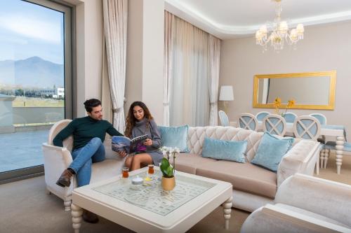 a man and woman sitting on a couch in a living room at Gabala Garden Hotel in Gabala