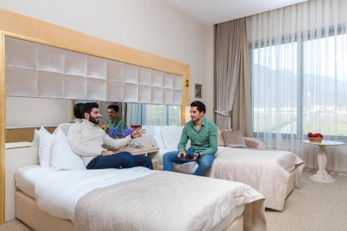 two men sitting in a hotel room with two beds at Gabala Garden Hotel in Gabala