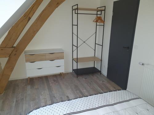 um quarto no sótão com uma cama e piso em madeira em L'élégant Gîtes de Moiscourt em Gisors
