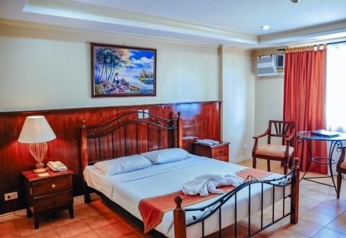 Crown Regency Residences Davao في مدينة دافاو: غرفة نوم بسرير وطاولة وكراسي