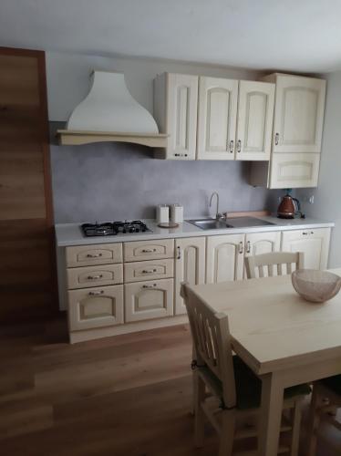 a kitchen with white cabinets and a table and a sink at Casa Caliman in Santa Caterina