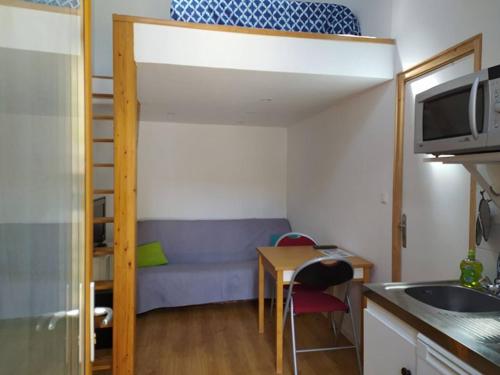 ein kleines Zimmer mit einem Etagenbett und einem Tisch in der Unterkunft Studio privé à la campagne in Guillerval