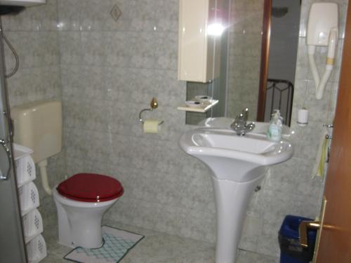 baño con lavabo y aseo con asiento rojo en Apartment Roby, en Vrsar