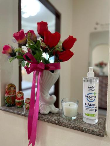 a vase with red roses and a candle on a shelf at Malinee Villa Phuket in Bang Tao Beach