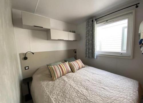 ein kleines Schlafzimmer mit einem Bett und einem Fenster in der Unterkunft Prachtig nieuw chalet met tuin op De Friese Wadden in Tzummarum