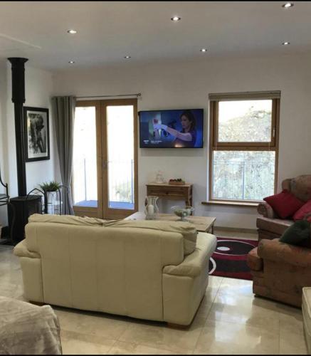 a living room with a couch and a tv on the wall at Seaside Serenity Escape in Fahan in Fahan