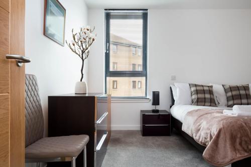 een slaapkamer met een bed, een bureau en een raam bij No. 5 Warriston, Canonmills Luxury Apartment in Edinburgh