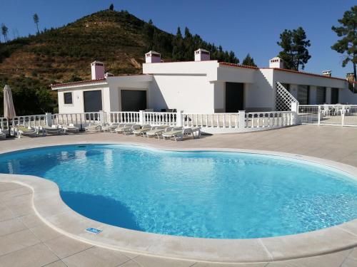 a large swimming pool in front of a house at Lago Azul Villas in Ferreira do Zêzere