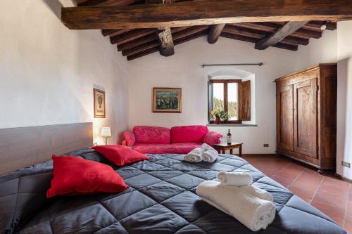 ein Schlafzimmer mit einem großen Bett und einem roten Sofa in der Unterkunft Podere Querceto in Monsanto