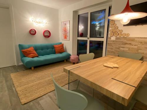 un salon avec une table et un canapé bleu dans l'établissement TRILOCALE SULLE PISTE Appena RISTRUTTURATO, à Sauze dʼOulx
