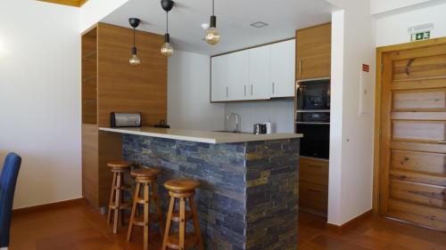 a kitchen with a stone counter and stools at Lago Azul Villas in Ferreira do Zêzere