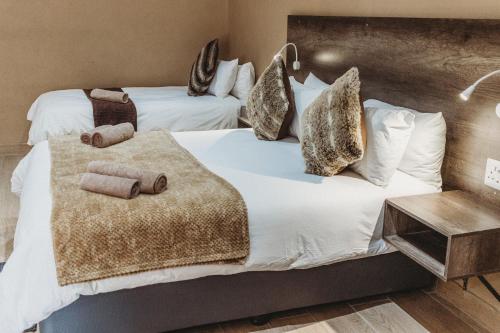 a bedroom with two beds with white sheets and pillows at Casa Leitao Lodge in Phalaborwa