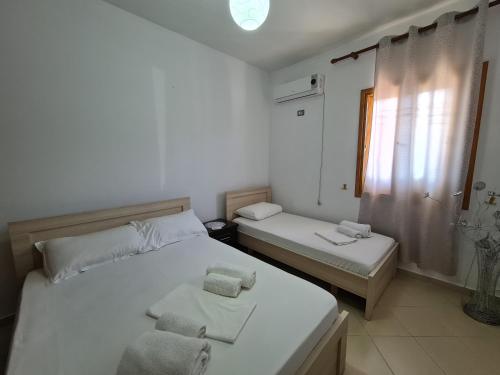 two beds in a small room with a window at Guesthouse Emanuel in Ksamil