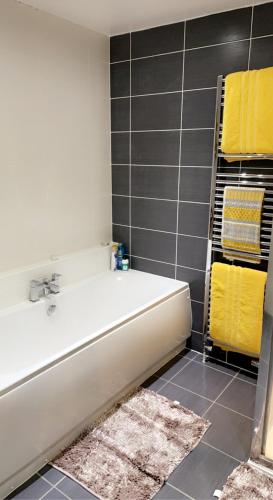 a white bath tub in a bathroom with yellow towels at Wallace View - Holiday Home in Stirling