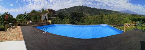 a large swimming pool with a mountain in the background at Case Vacanze Fossanave in Santa Tecla