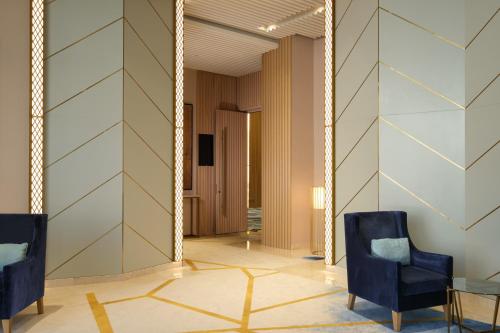 a hallway with two chairs and a mirror at Maani Muscat Hotel & Suites in Muscat