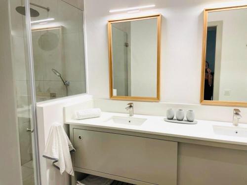 a white bathroom with two sinks and a shower at East Coast Beachfront Luxury - Eastern Blue Apartments in Poste Lafayette