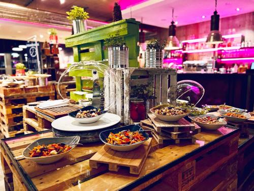 a buffet with bowls of food on a table at Altes Stahlwerk Business & Lifestyle Hotel in Neumünster