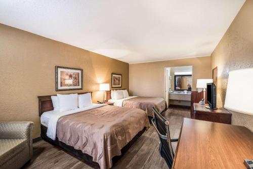 a hotel room with two beds and a table at Quality Inn Arkadelphia - University Area in Arkadelphia