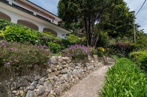 a stone wall in front of a house with flowers at Vivenda Santiago in Sesimbra