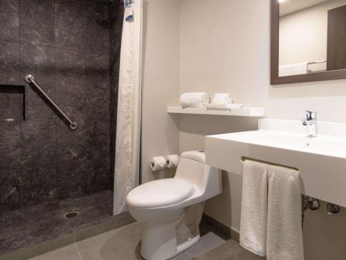 a bathroom with a toilet and a sink and a shower at Sleep Inn Guadalajara Galerias in Guadalajara