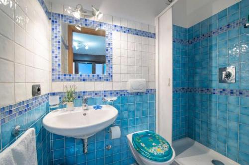 bagno piastrellato blu con lavandino e servizi igienici di Il piccolo Sogno in costiera Amalfitana a Conca dei Marini