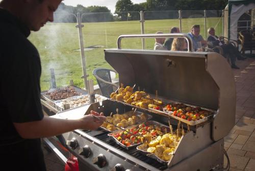 a person is cooking food on a grill at Landhotel Möllhagen in Schülp