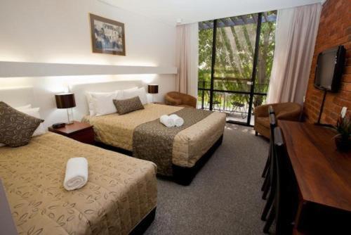 a hotel room with two beds and a television at Connells Motel & Serviced Apartments in Traralgon