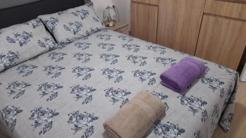 a bed with blue and white sheets and pillows at Apartmani Orion-Tara in Bajina Bašta