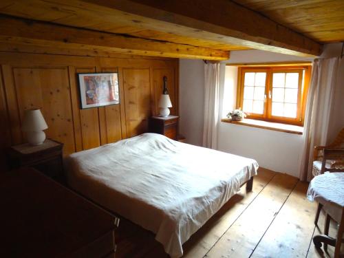 a bedroom with a white bed and a window at Haus Nicca in Splügen
