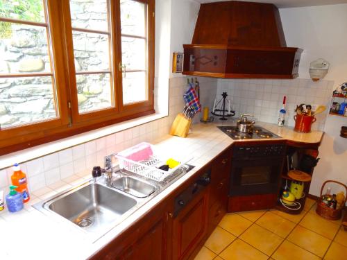 a kitchen with a sink and a stove and windows at Haus Nicca in Splügen