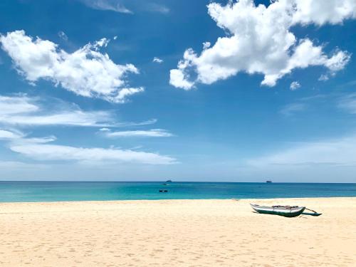 トリンコマリーにある108 Palms Beach Resortの海辺の砂浜に座る船