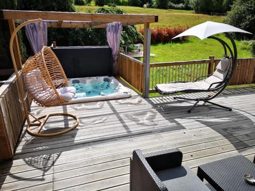 a deck with a hammock chairs and a hot tub at MONTAGNE-LAC&SPA (jacuzzi privé) (NOUVEAU) in Anould