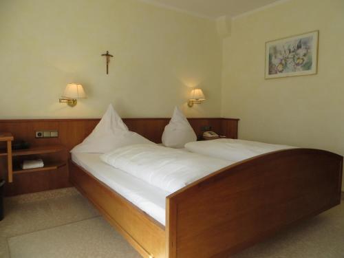 1 dormitorio con 1 cama con sábanas blancas y una cruz en la pared en Kneippblick en Bad Wörishofen